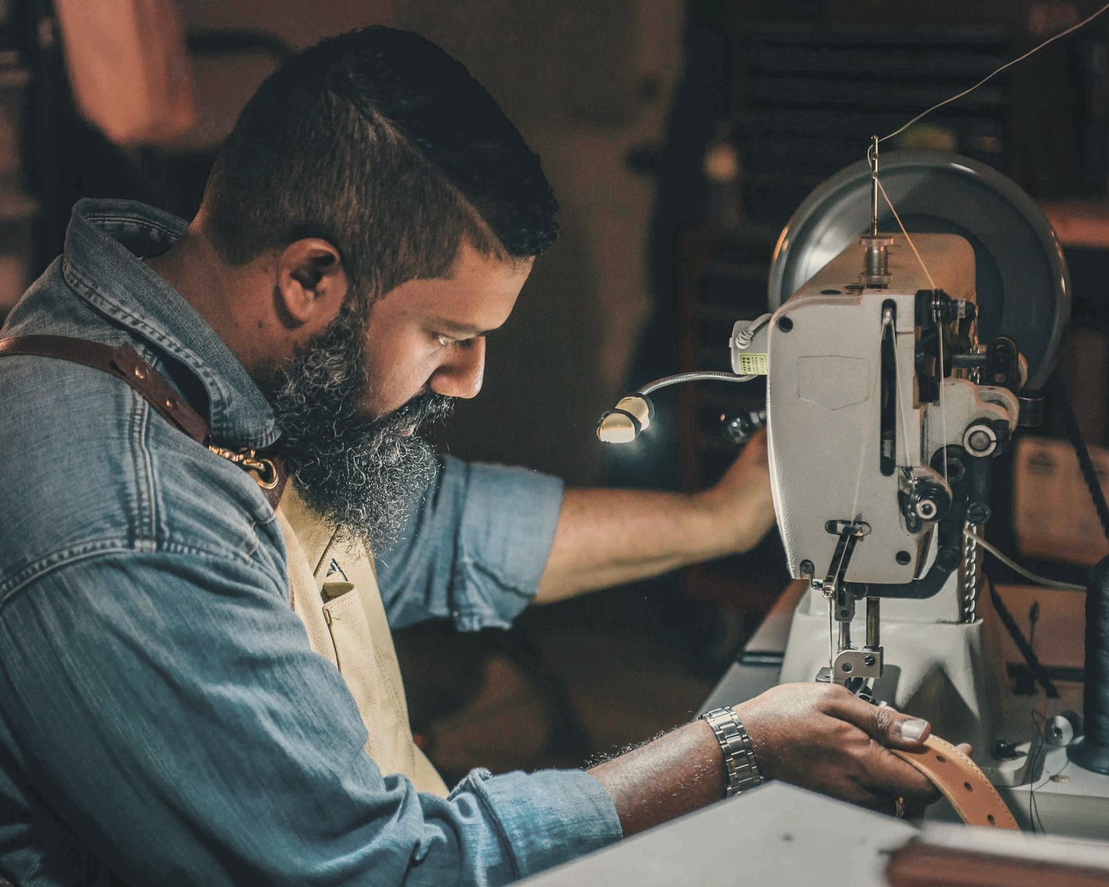 Leather belt being fed through an industrial sewing machine