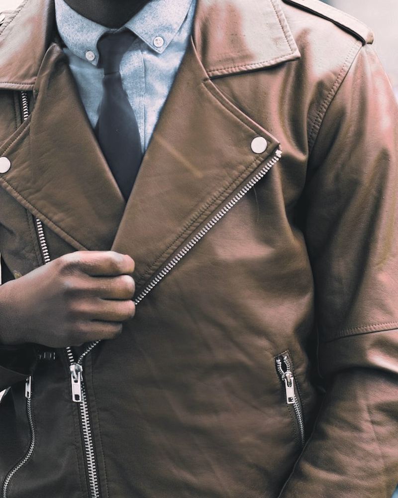 Cognac cowhide biker jacket with snap lapels and an asymmetric zip, worn over a blue shirt