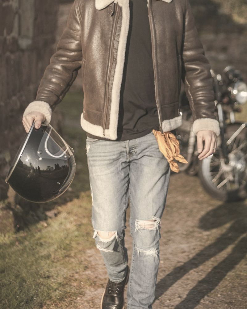 A customer walking in his shearling-collar jacket with a helmet in hand