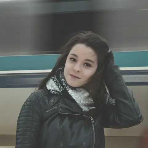 Customer in a black biker jacket, smiling, hand in her hair