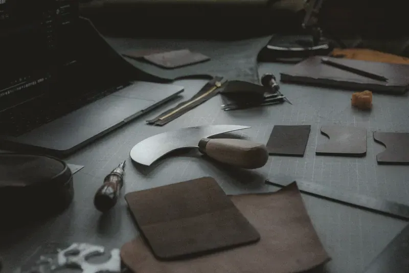 A cutting knife, pattern pieces and tools on a dark workbench