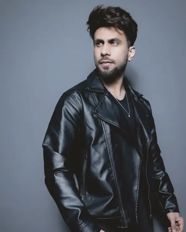Black leather biker jacket worn open over a black top, three-quarter view in a blue-grey studio