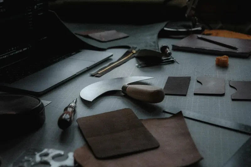Cutting tools and pieces of leather on a grey bench
